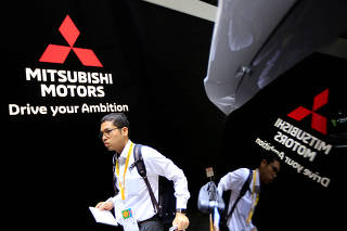 FILE PHOTO: A man walks near Mitsubishi cars as he visits Tokyo Motor Show in Tokyo