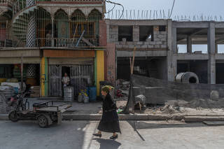 A Uighur woman walks past construction of new buildings in Yarkand, in the Xinjiang region of China, on Aug. 5, 2019. (Gilles Sabrié/The New York Times)