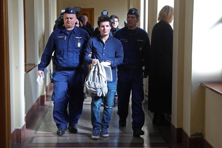 Rui Pinto (ao centro) é escoltado por policiais ao chegar à corte de Justiça em Budapeste, na Hungria