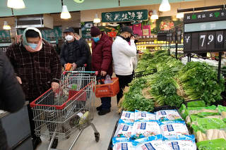 FILE PHOTO: People wearing masks shop at a supermarket on the second day of the Chinese Lunar New Year, following the outbreak of a new coronavirus, in Wuhan, Hubei