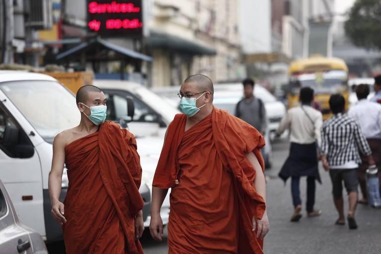 Monges budistas usam máscaras enquanto andam em uma rua de Rangum, Mianmar,em 29 de janeiro de 2020