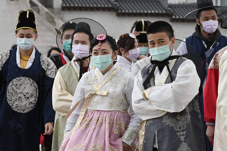 Turistas em trajes tradicionais coreanos usam máscaras faciais enquanto visitam o palácio Gyeongbokgung, em Seul, em 30 de janeiro de 2020
