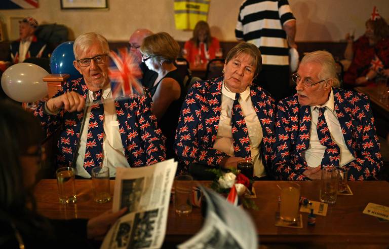 Homens vestidos com jaquetas da bandeira britânica durante a celebração no Woolston Social Club em Warrington, noroeste da Inglaterra 