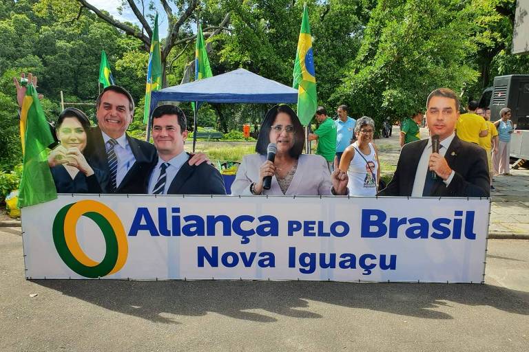 Na placa lê-se "Aliança pelo Brasil Nova Iguaçu". Da esquerda para a direita vê-se as fotos de Michelle e Jair Bolsonaro, Sergio Moro, Damares Alves e Flávio Bolsonaro