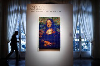 A man walks by the Rubik Mona Lisa (2005) by French street artist Invader displayed at ArtCurial in Paris