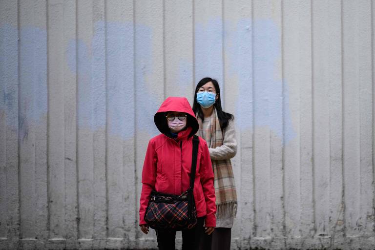 Duas pedestres com máscaras esperam para atravessar a rua em Hong Kong, região especial chinesa