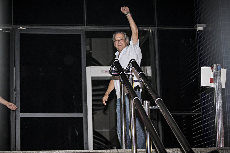 O ex-ministro-chefe da Casa Civil, José Dirceu, saúda militantes ao chegar à sede da Polícia Federal, em São Paulo. O STF determinou sua prisão por envolvimento no esquema de corrupção do Mensalão