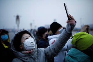 A woman wearing a face mask uses her cellphone at the Tiananmen Square, as the country is hit by an outbreak of the new coronavirus, in Beijing