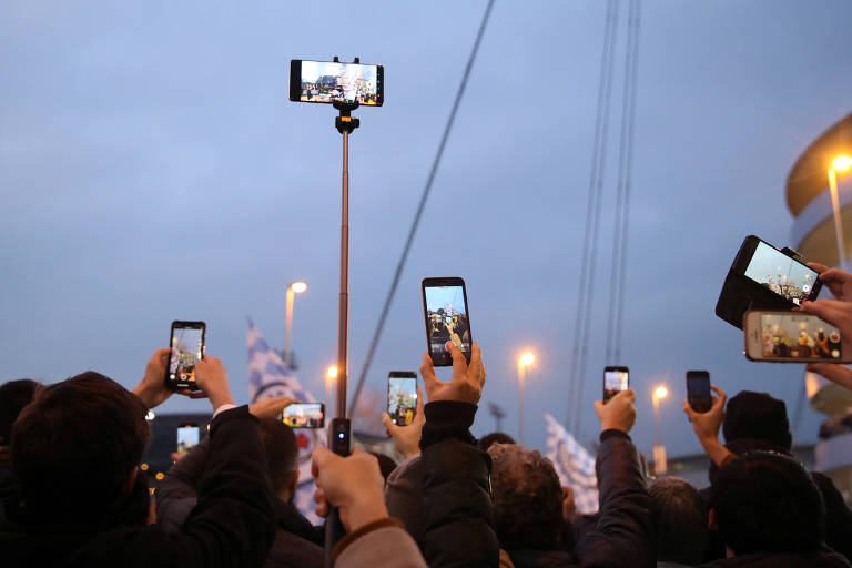 Torcedores ingleses usam celulares antes de jogo de futebol em Manchester 