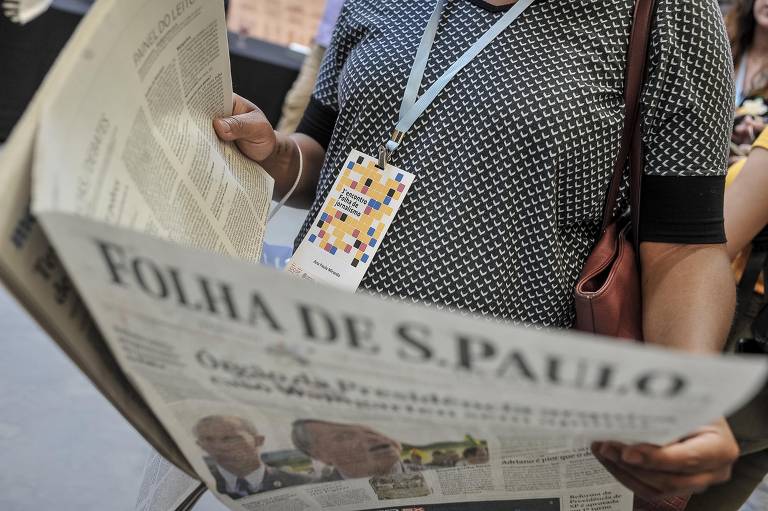 Participante do Encontro Folha de Jornalismo, em São Paulo, lê a edição impressa do jornal