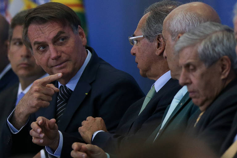 O presidente Jair Bolsonaro aponta o dedo para os ministros Paulo Guedes (Economia), Luiz Eduardo Ramos (Secretaria de Governo) e Augusto Heleno (GSI) durante cerimônia de lançamento de programa de crédito imobiliário da Caixa Econômica Federal, em Brasília