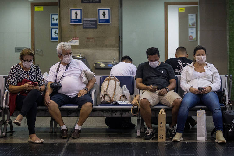 Passageiros usam máscara de proteção no aeroporto de Guarulhos após casos confirmados de coronavírus no Brasil