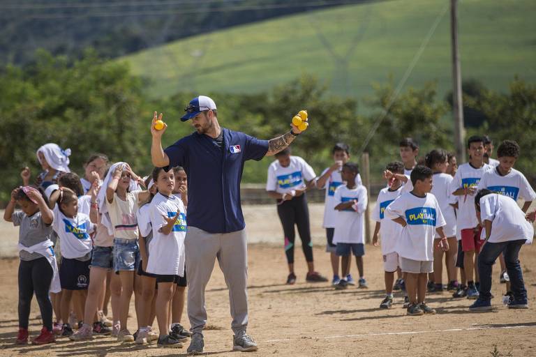 O arremessador brasileiro André Rienzo, 31, orienta crianças durante evento da MLB (liga americana de beisebol) em Atibaia, no interior de São Paulo
