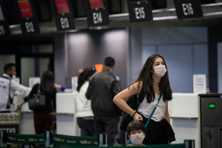 Passageiros e funcionários usam máscaras enquanto esperam voo no Aeroporto Internacional de Guarulhos, na Grande SP; ela deve ser usada por quem tem sintomas da doença e voltou de país com casos de coronavírus 