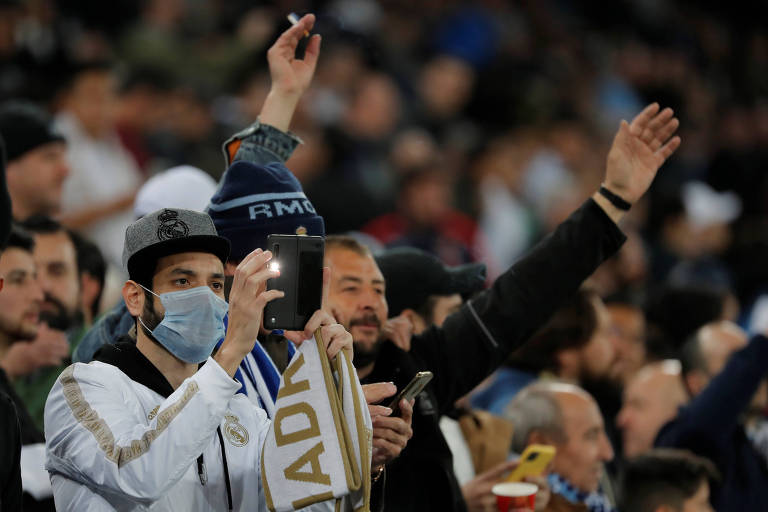 Fã do Real Madrid usa máscara em meio epidemia do novo coronavírus durante o primeiro jogo das oitavas-de-final da Liga dos Campeões entre Real Madrid e Manchester City -