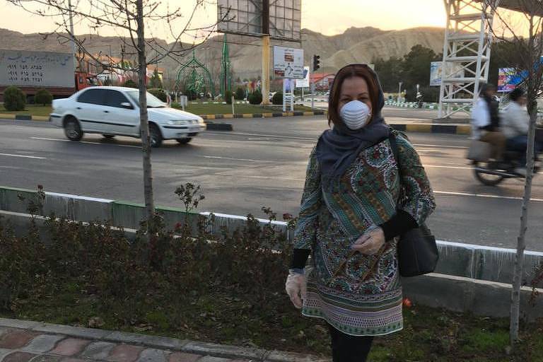 Mulher com máscara em frente a uma rua