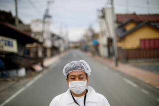 Yuji Onuma, an evacuee from Futaba Town near tsunami-crippled Fukushima Daiichi nuclear power plant, poses for a photograph on the empty street in Fuutaba Town, Fukushima, Japan