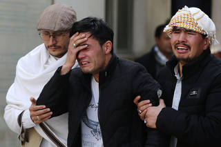 Afghan men cry at a hospital after they heard that their relative was killed during an attack in Kabul, Afghanistan