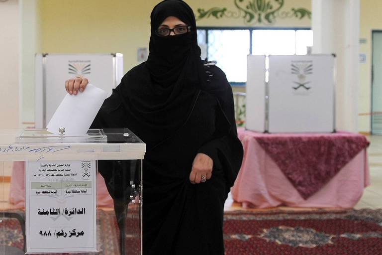 Mulheres passam a votar na Arábia Saudita 
Eleitora deposita cédula em urna durante eleições na Arábia Saudita em 2015, quando as mulheres foram autorizadas a votar pela primeira vez na história do país, um reino islâmico ultraconservador