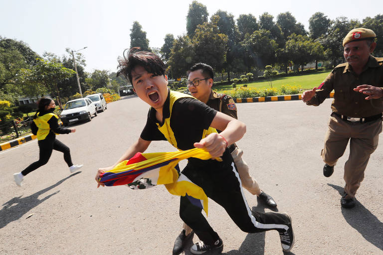 Policiais prendem manifestante tibetano em frente à embaixada da China em Déli durante protesto que marca o 61º do levante do Tibete contra o domínio chinês
