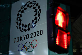 A banner for the upcoming Tokyo 2020 Olympics is seen through a traffic signal in Tokyo