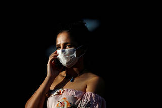 A woman talks on the phone while wearing a protective face mask at the North Wing Regional Hospital after reports of the coronavirus in Brasilia