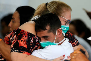 People wearing protective face masks hug at the North Wing Regional Hospital in Brasilia