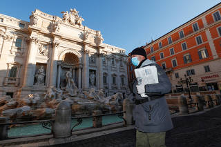 A man wearing a protective face mask walks next to the Trevi fountain, virtually deserted as Italy fights a coronavirus outbreak, in Rome