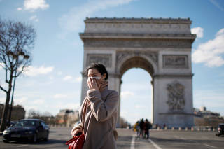 A woman wearing a protective mask, walks near Arc de Triomphe as France grapples with an outbreak of coronavirus (COVID-19) disease, in Paris