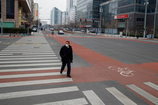 FILE PHOTO: A man wears a face mask as he crosses a street in the Central Business District in Beijing as the country is hit by an outbreak of the novel coronavirus