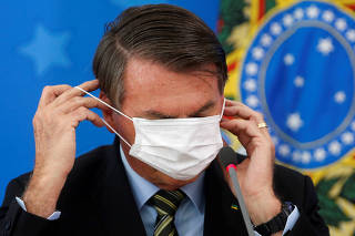 Brazil's Jair Bolsonaro adjusts his protective face mask during a press conference to announce measures to curb the spread of the coronavirus disease (COVID-19) in Brasilia