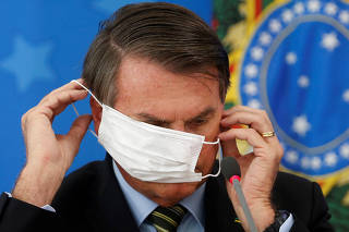 Brazil's President Jair Bolsonaro wearing a protective face masks reacts during a news conference to announce measures to curb the spread of the coronavirus disease (COVID-19) in Brasilia
