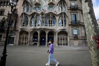 Woman wears a protective face mask as she walks past an empty The Casa Batllo, amidst concerns over Spain's coronavirus outbreak, in Barcelona