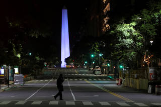A police officer is silhouetted while walking in front of Buenos Aires' historical Obelisk after Argentina's President Alberto Fernandez announced a mandatory quarantine as latest measure to curb the spread of coronavirus disease (COVID-19), in Argentina