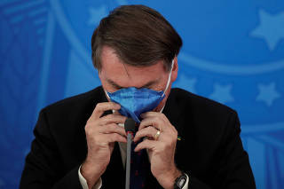 Brazil's President Jair Bolsonaro adjusts his protective face mask during a news conference, amid coronavirus disease (COVID-19) outbreak, in Brasilia