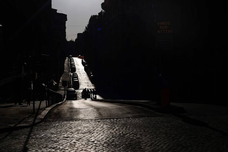 Policial verifica pedestres que atravessam uma rua deserta em Roma, durante o bloqueio do país com o objetivo de impedir a propagação da pandemia de Covid-19

