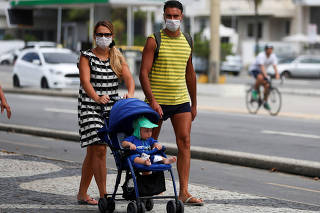 A couple wearing protective face masks walk with their child along the Copacabana beach following the closure of the beaches amid the coronavirus disease (COVID-19) outbreak, in Rio de Janeiroo