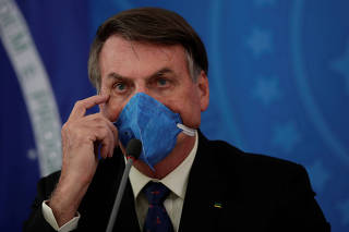 Brazil's President Jair Bolsonaro gestures as he wears a protective mask during a news conference, amid coronavirus disease (COVID-19) outbreak, in Brasilia