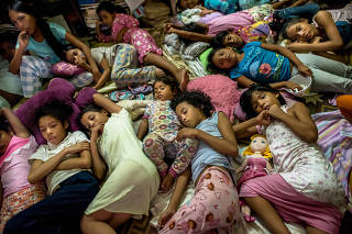 Ana, center front, comforts one of the youngest girls while they watch a movie in their pajamas before bed, at the Casa Hogar Carmela Valera in Maracaibo, Venezuela on Feb. 6, 2020. (Meridith Kohut/The New York Times)