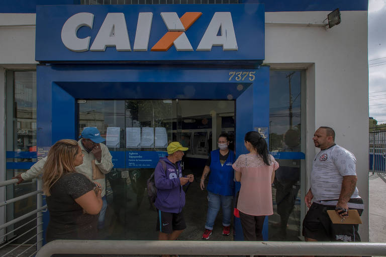 Clientes aguardam autorização para entrar em agência da Caixa na zona leste de São Paulo em dia de saque de benefícios do INSS