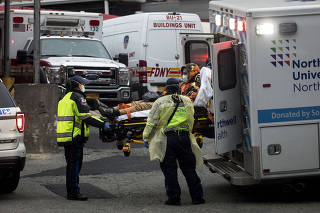 A person wearing a medical mask is unloaded from an amulance outside of Elmhurst Hospital Center in New York, March 25, 2020. (Dave Sanders/The New York Times)