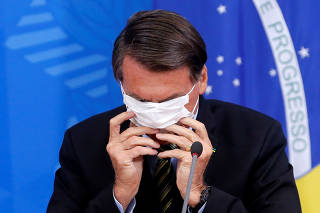 Brazil's President Jair Bolsonaro adjusts his protective face mask during a press statement to announce federal judiciary measures to curb the spread of the coronavirus disease (COVID-19) in Brasilia