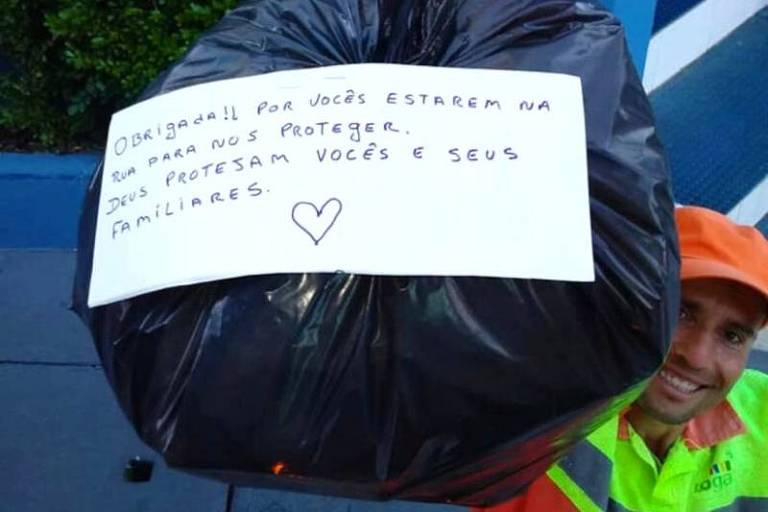 Funcionário da coleta de lixo mostra saco com mensagem de morador em São Paulo