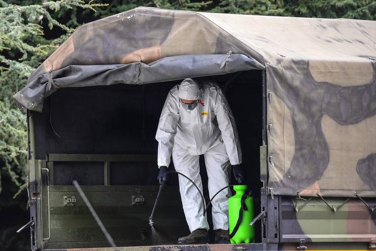 Homem desinfeta caminhão do Exército italiano no Cemitério Monumental de Bergamo, de onde levaria caixões com corpos de mortos pelo novo coronavírus rumo a outras regiões