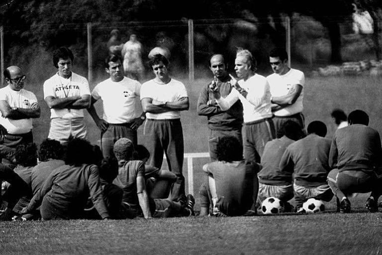 Técnico na Copa de 1970, Zagallo, com os dedos em riste, orienta os jogadores em treino. Ao centro, de braços cruzados, observa o então preparador físico Carlos Alberto Parreira