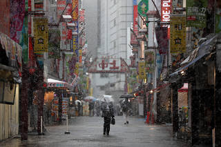 A man walks past on a nearly empty street in a snow fall during a coronavirus disease outbreak in Tokyo