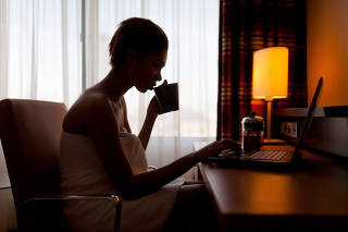 Young woman sitting at laptop in hotel room