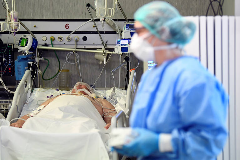 Profissional da área médica com equipamentos de proteção e paciente de Covid-19 em UTI no hospital Oglio Po, em Cremona, na Itália