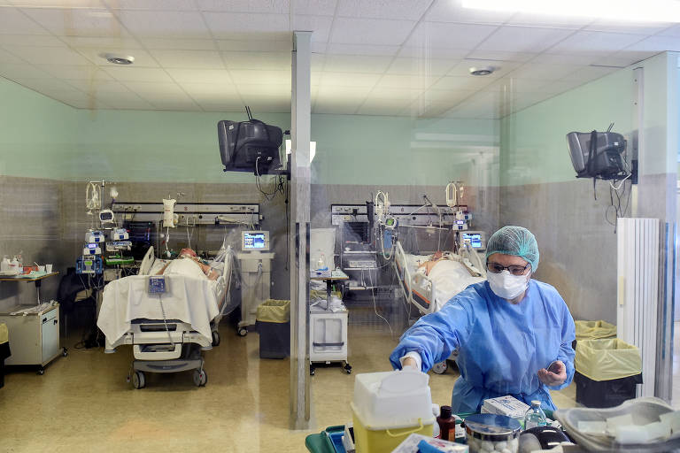 Profissional da área médica com equipamentos de proteção e pacientes de Covid-19 em UTI no hospital Oglio Po, em Cremona, na Itália