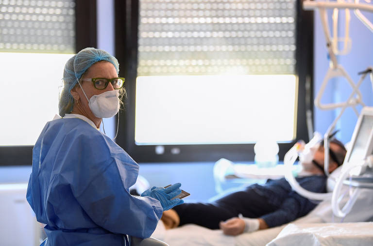 Profissional da área médica com equipamentos de proteção e paciente de Covid-19 em UTI no hospital Oglio Po, em Cremona, na Itália